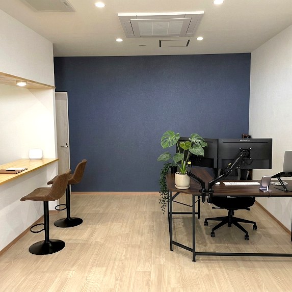 KofC事務所内部。ネイビーのアクセント壁・木目フローリング・打ち合わせカウンター